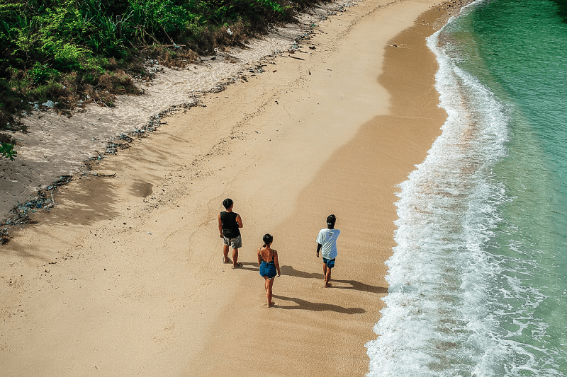Three people walking along the beach