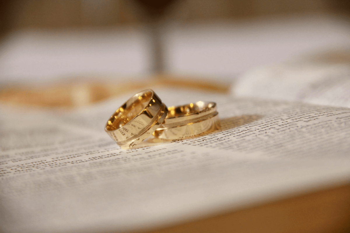 Two gold wedding rings lying together on a page of a book. Symbolising the good fortune of a Deaf Lottery Winner.
